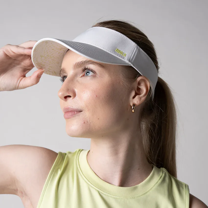 Người chơi đội mũ JOOLA Printed Brim Visor, tay nâng lưỡi trai